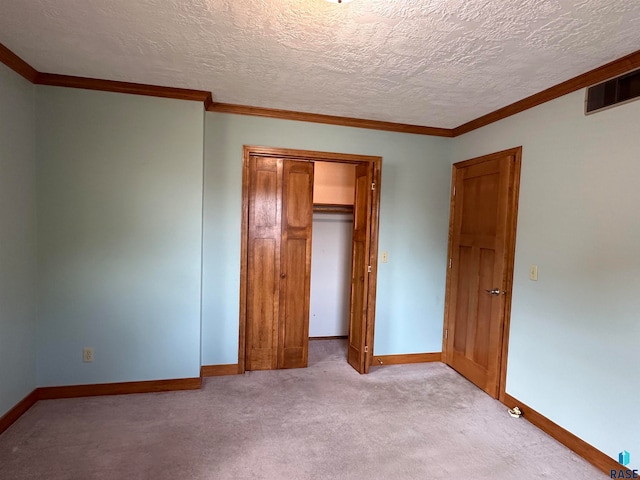 unfurnished bedroom featuring light carpet, a textured ceiling, a closet, and crown molding