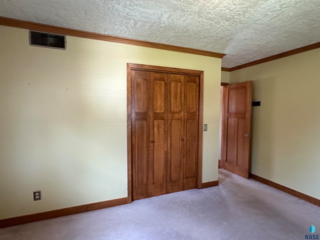 unfurnished bedroom with a textured ceiling and light colored carpet