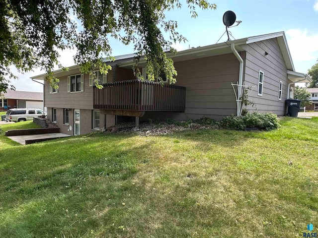 back of house featuring a lawn and a wooden deck