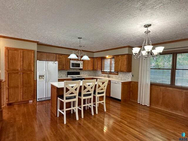 kitchen featuring a center island, white appliances, dark wood-type flooring, and decorative light fixtures