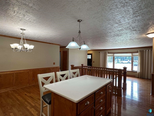 kitchen featuring crown molding, decorative light fixtures, dark wood-type flooring, and an inviting chandelier