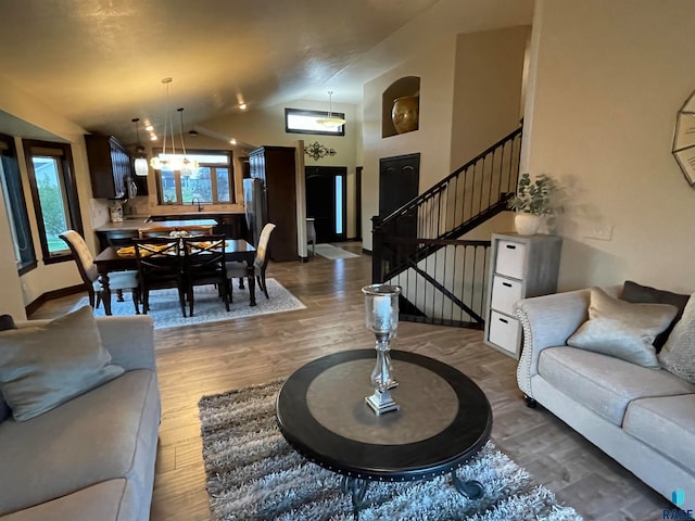 living room with high vaulted ceiling, an inviting chandelier, and dark hardwood / wood-style floors