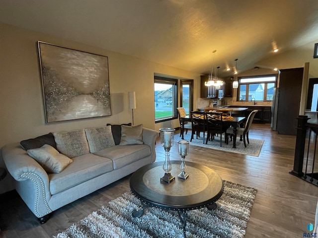 living room featuring sink, a notable chandelier, vaulted ceiling, and dark wood-type flooring