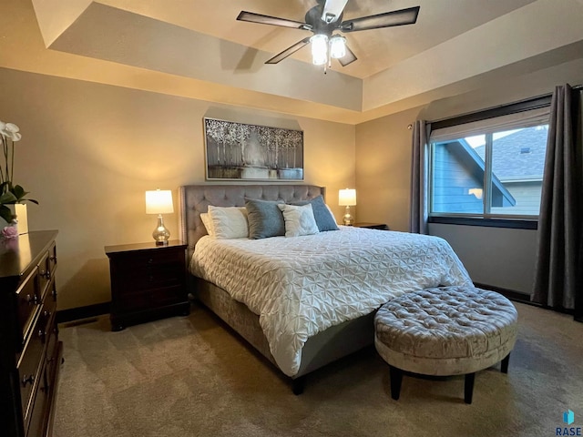 carpeted bedroom featuring ceiling fan and a tray ceiling