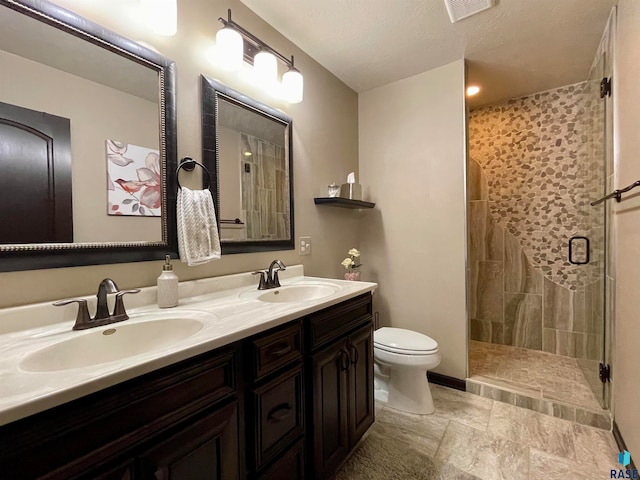 bathroom featuring toilet, tile patterned flooring, vanity, a textured ceiling, and a shower with shower door