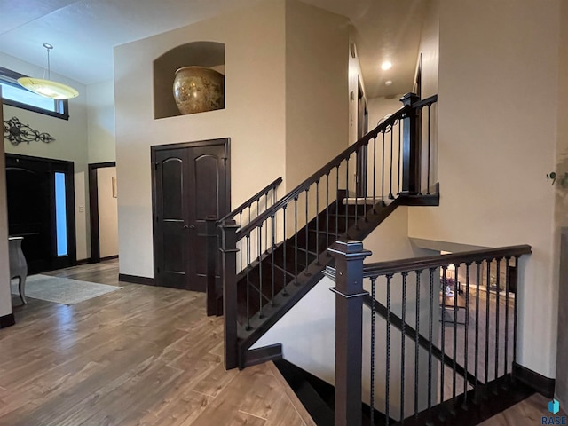 entrance foyer featuring a towering ceiling and wood-type flooring