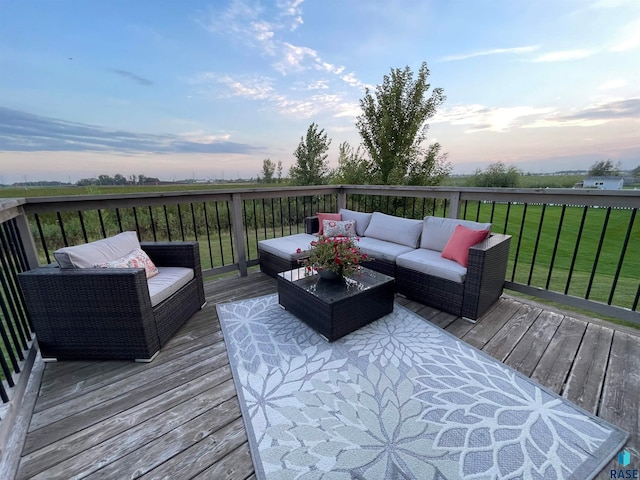 deck at dusk with an outdoor living space and a lawn