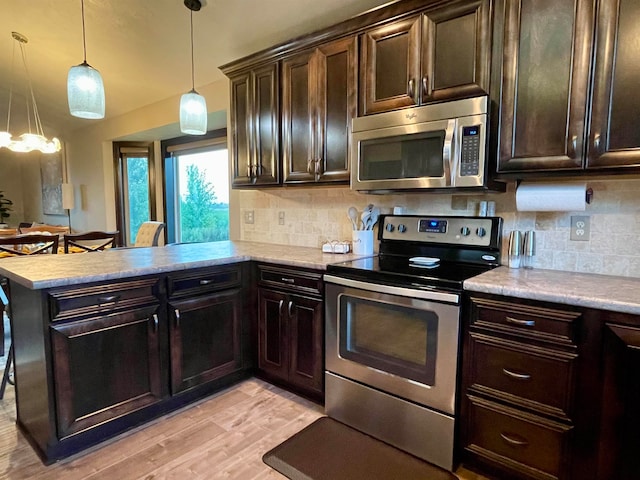 kitchen featuring appliances with stainless steel finishes, decorative backsplash, hanging light fixtures, and dark brown cabinetry