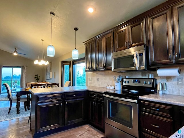 kitchen featuring decorative backsplash, dark brown cabinetry, pendant lighting, lofted ceiling, and stainless steel appliances