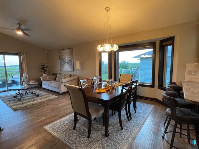 dining space with hardwood / wood-style floors, vaulted ceiling, a notable chandelier, and a healthy amount of sunlight