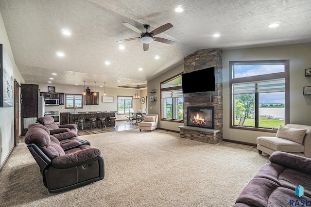 living room featuring ceiling fan, light colored carpet, a textured ceiling, and a fireplace