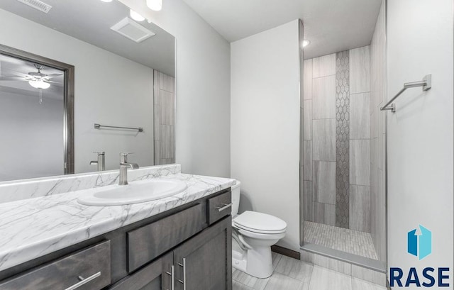 bathroom featuring vanity, toilet, tiled shower, and ceiling fan