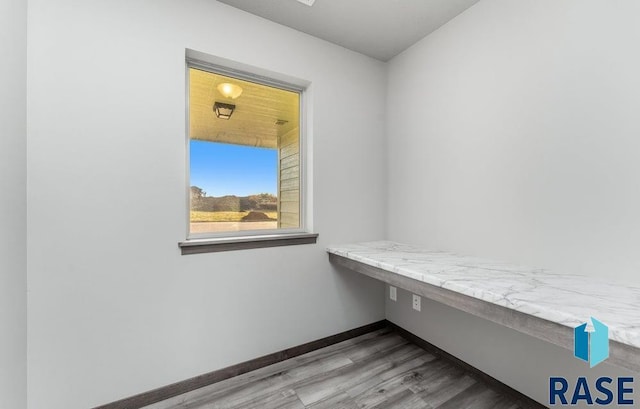 interior space featuring baseboards, built in desk, and wood finished floors