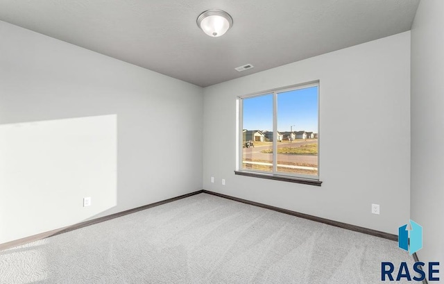 carpeted spare room with baseboards and visible vents