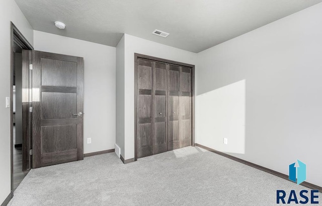 unfurnished bedroom with a closet and light colored carpet