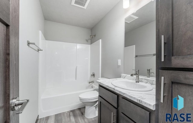 full bathroom featuring visible vents, vanity, wood finished floors, toilet, and bathtub / shower combination