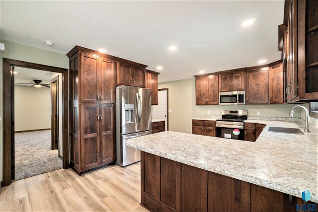 kitchen featuring light carpet, stainless steel appliances, sink, kitchen peninsula, and ceiling fan