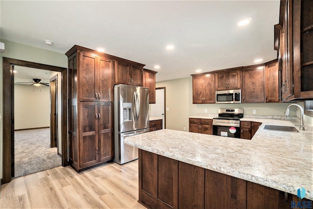 kitchen with light wood finished floors, light countertops, appliances with stainless steel finishes, and a sink