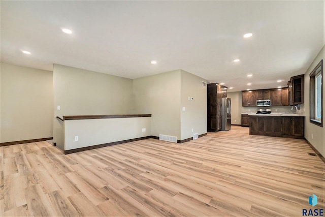 kitchen with dark brown cabinetry, visible vents, appliances with stainless steel finishes, and open floor plan