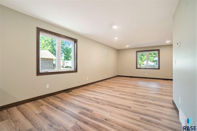 empty room featuring light wood finished floors, baseboards, and recessed lighting