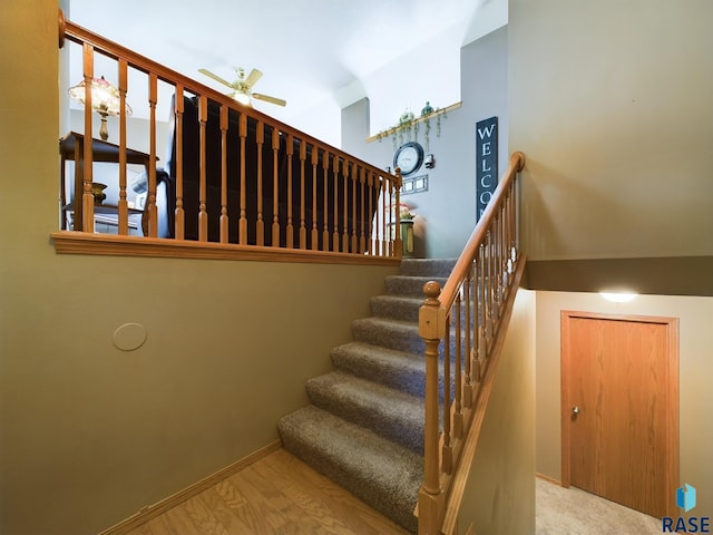 stairs featuring hardwood / wood-style floors and ceiling fan