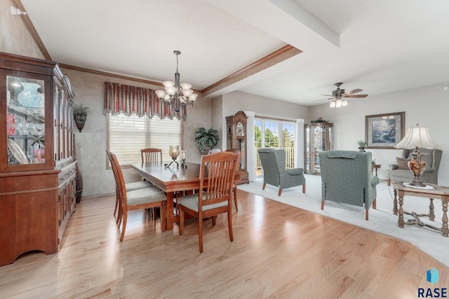 dining space with ceiling fan with notable chandelier, crown molding, and light hardwood / wood-style flooring