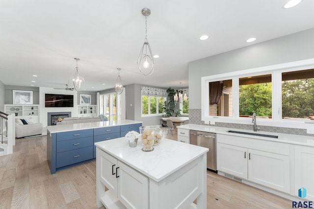 kitchen with a sink, white cabinetry, open floor plan, a center island, and dishwasher