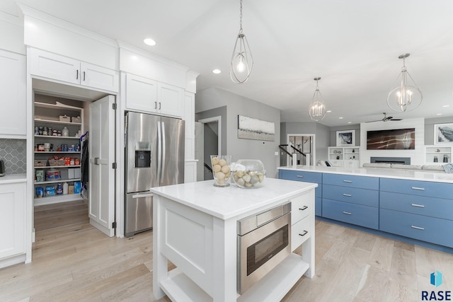 kitchen with a kitchen island, white cabinetry, stainless steel appliances, and pendant lighting