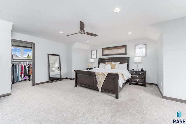 bedroom with recessed lighting, light colored carpet, a ceiling fan, baseboards, and a walk in closet