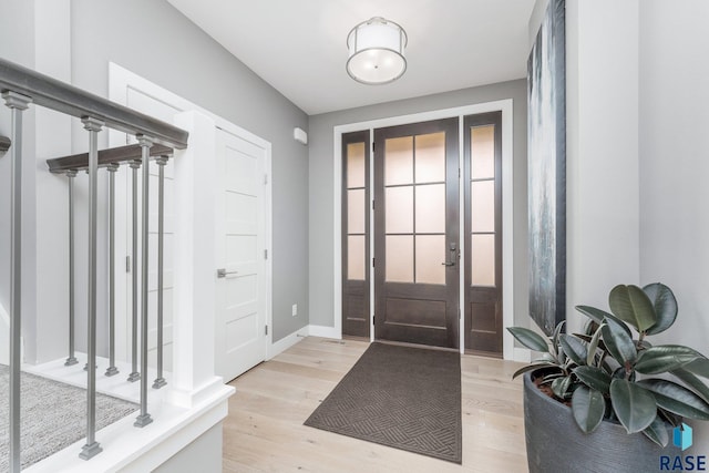 entrance foyer with baseboards, stairs, and light wood-style floors