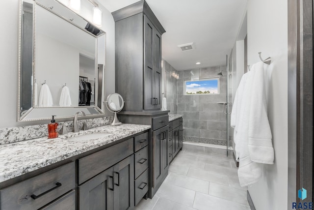 bathroom with visible vents, tile patterned floors, a spacious closet, vanity, and a shower stall