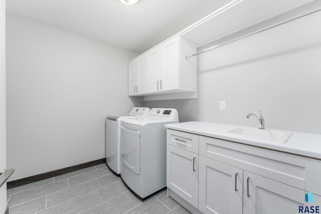 washroom with washer and clothes dryer, a sink, cabinet space, and baseboards