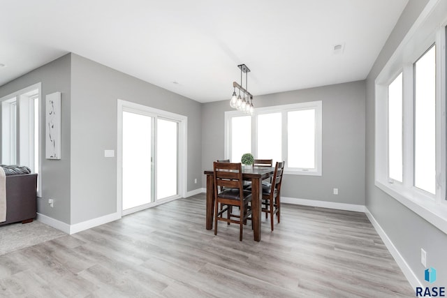 dining space featuring light wood-style floors, plenty of natural light, and baseboards