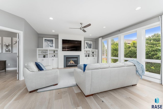 living room with light wood finished floors, baseboards, a ceiling fan, a fireplace, and recessed lighting