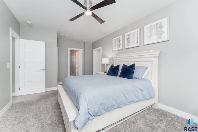 carpeted bedroom with ceiling fan, ensuite bath, and baseboards