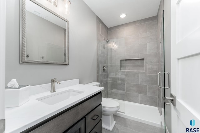 full bath with toilet, tile patterned flooring, tiled shower, and vanity