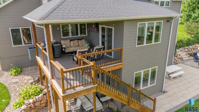 wooden deck with an outdoor living space, a patio, and stairway