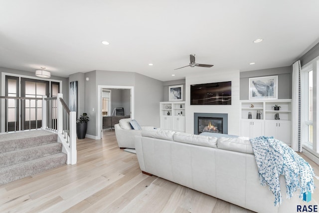 living area with recessed lighting, a large fireplace, stairway, and light wood finished floors