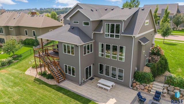 back of property with roof with shingles, a yard, a patio, a residential view, and stairs