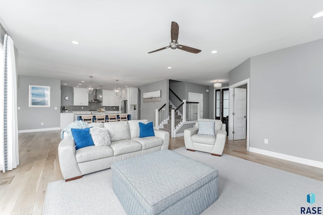 living room with light wood-type flooring, baseboards, stairway, and recessed lighting