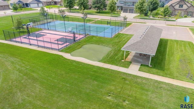 view of community featuring a tennis court, fence, and a residential view