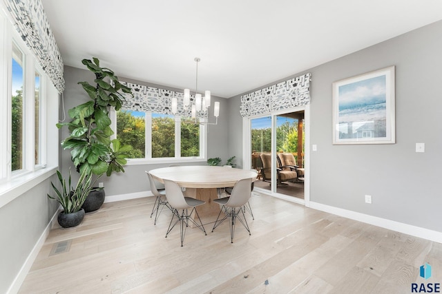 dining area featuring baseboards, a notable chandelier, visible vents, and light wood finished floors