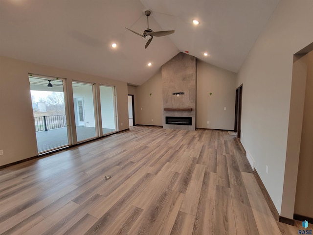 unfurnished living room featuring ceiling fan, high vaulted ceiling, a tile fireplace, baseboards, and light wood-type flooring