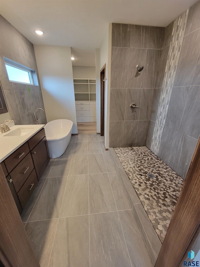 full bath with a soaking tub, a spacious closet, walk in shower, and vanity