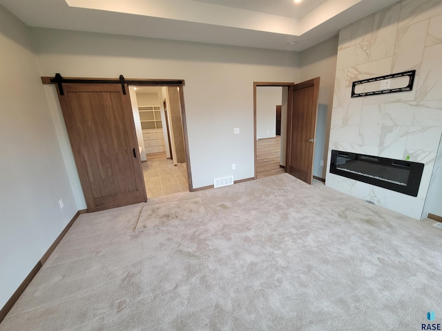 interior space featuring a barn door, a fireplace, visible vents, baseboards, and carpet