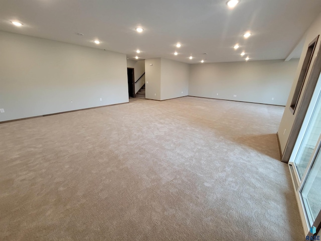 basement featuring recessed lighting, light colored carpet, stairway, and baseboards