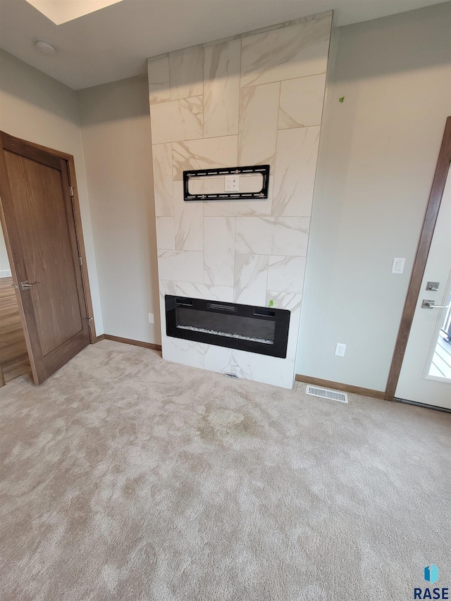 unfurnished living room with carpet, a fireplace, visible vents, and baseboards