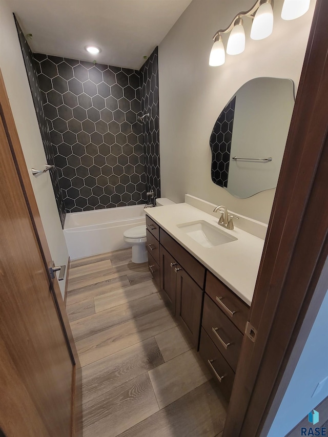 bathroom featuring toilet, shower / bathing tub combination, wood finished floors, and vanity