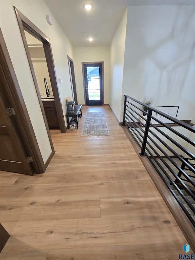 8106 E Norway Pines Trl, Sioux Falls, SD 57110 - hallway with baseboards, an upstairs landing, and light wood-style floors
