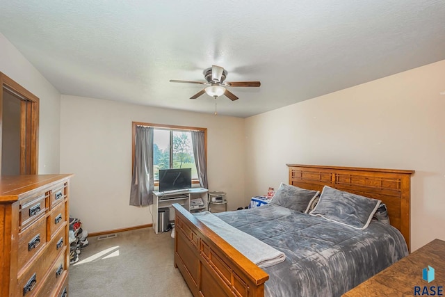 bedroom with a textured ceiling, ceiling fan, and light carpet